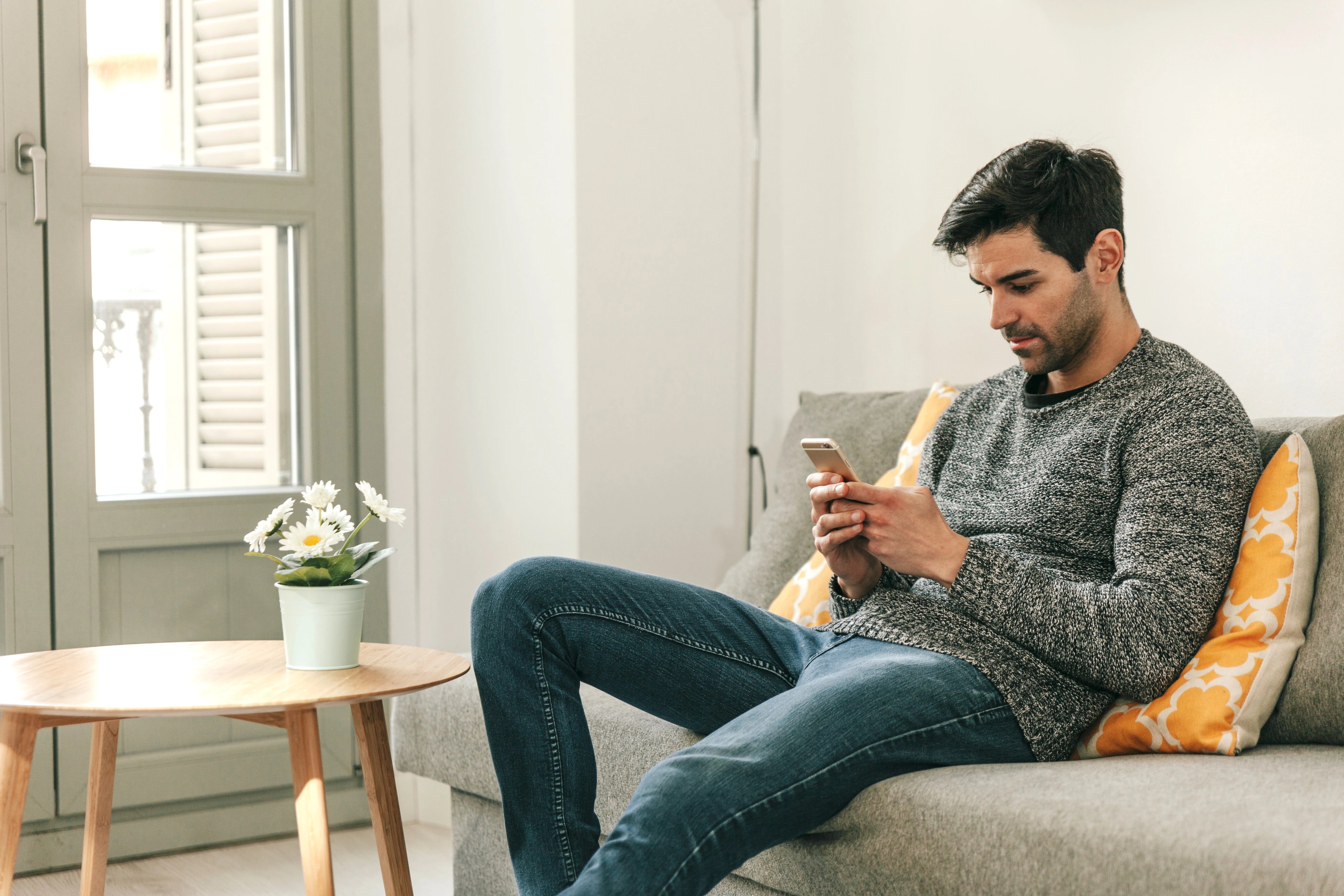 man-with-smartphone-resting-sofa-1